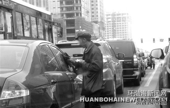 在建设路新华道路口“擦车”的行乞者。田菲菲摄